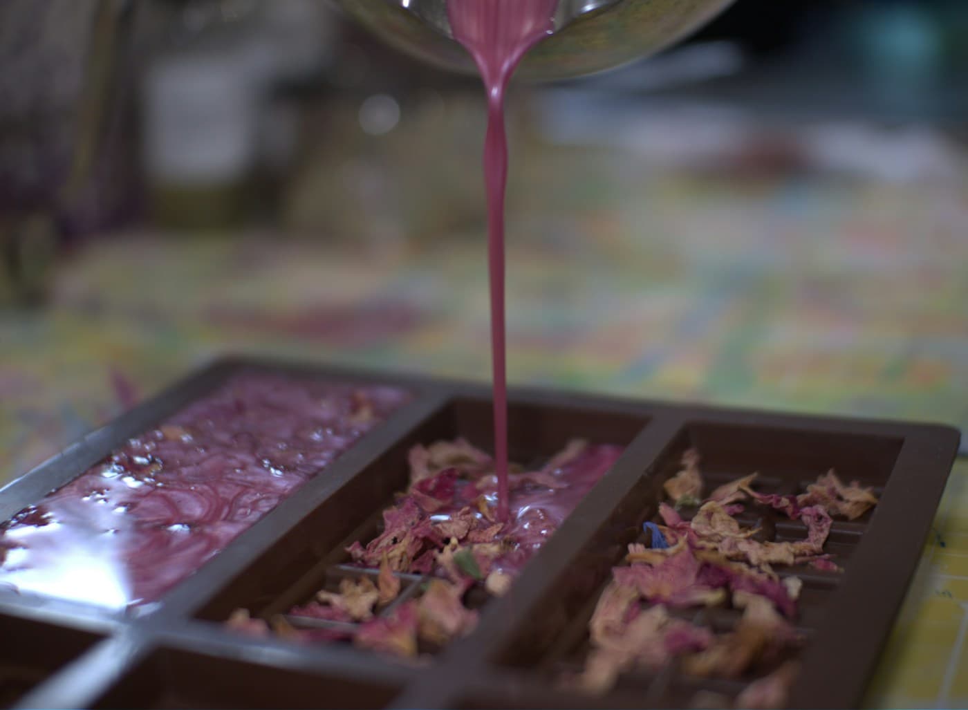 Pink wax being poured into a mould lined with dried petals